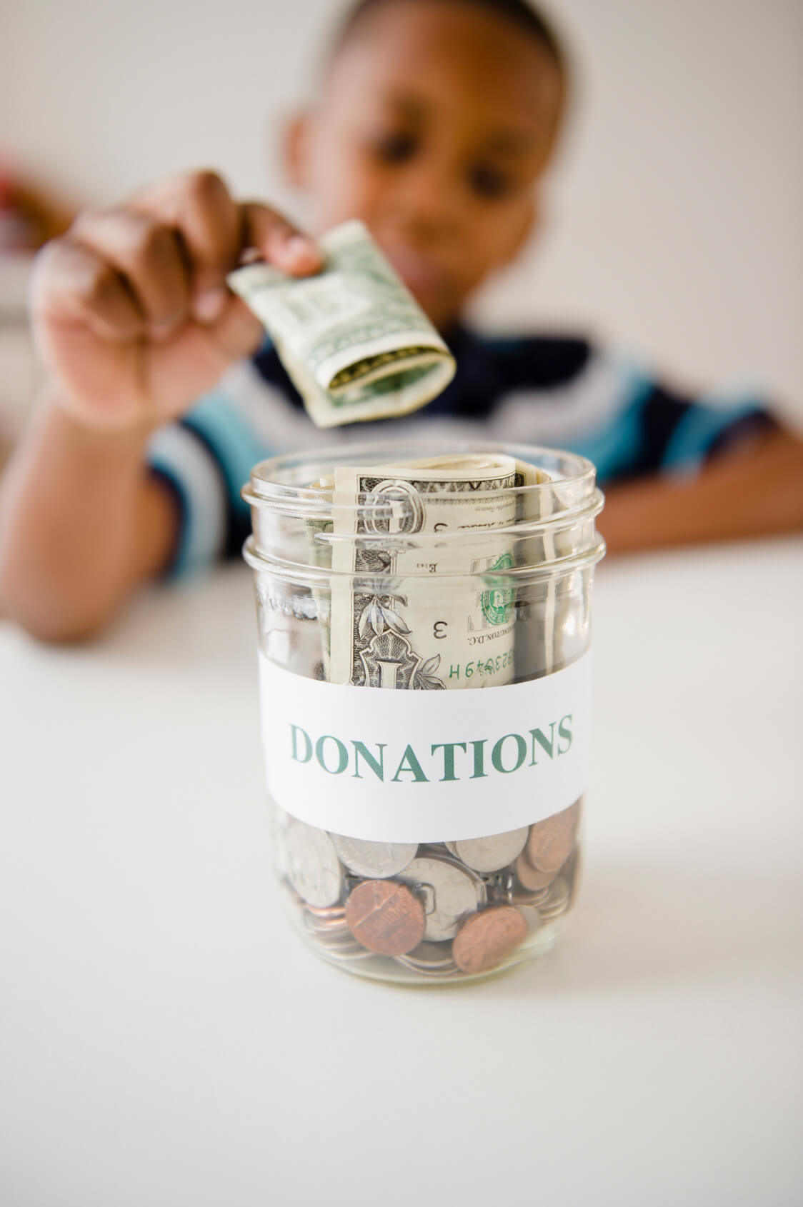 A person putting money into a donations jar.
